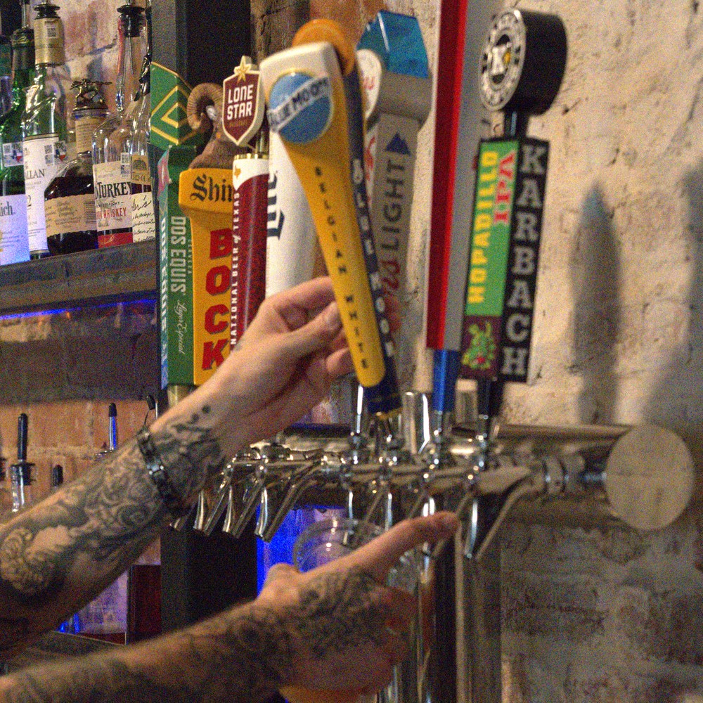 A bartender pulling a cold draft from the tap wall