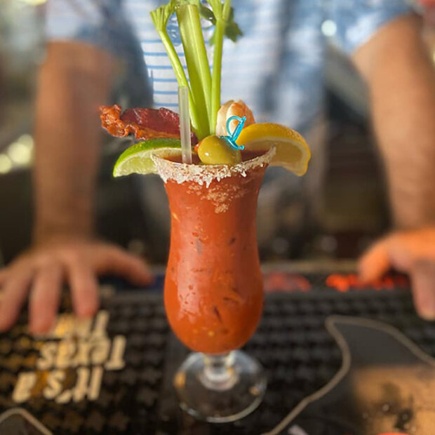A bloody mary built tall with bacon, celery, shrimp, olive and citrus